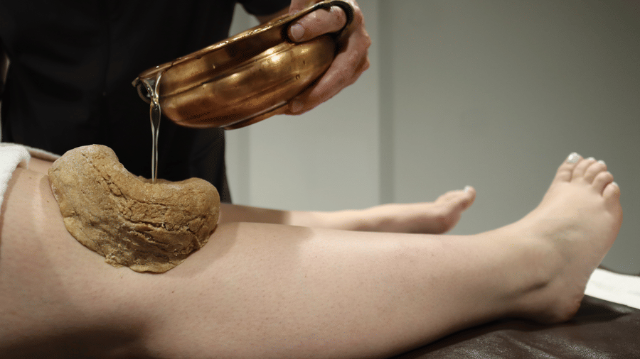 A spa treatment where herbal oil is being applied to a leg at YO1 Longevity & Health Resorts, offering relaxation and wellness services.