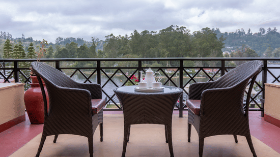 An image of a balcony featuring two chairs and a centre table from where outdoor view can be enjoyed - The Carlton