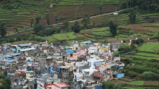 Close view of a hillside town with tightly packed houses, bordered by stepped agricultural fields in Kodaikanal, Tamil Nadu.