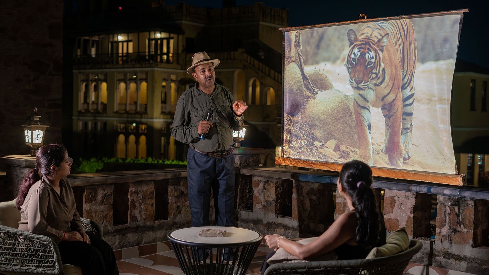 Picture of a naturalist giving a presentation to guests outdoors, with a tiger image projected on the screen.