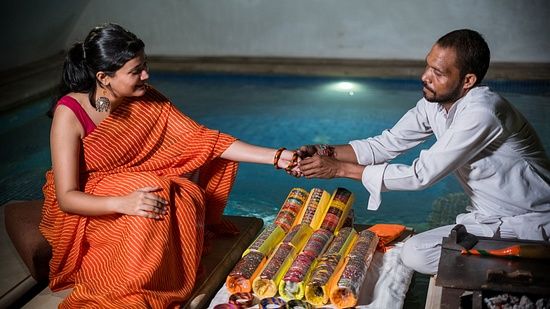 A bangle maker placing bangles on a woman's hand, with a table full of colorful bangles beside him