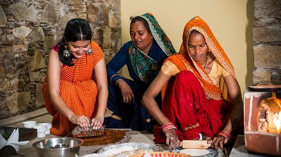 Three people sitting together on the floor and making chapatis
