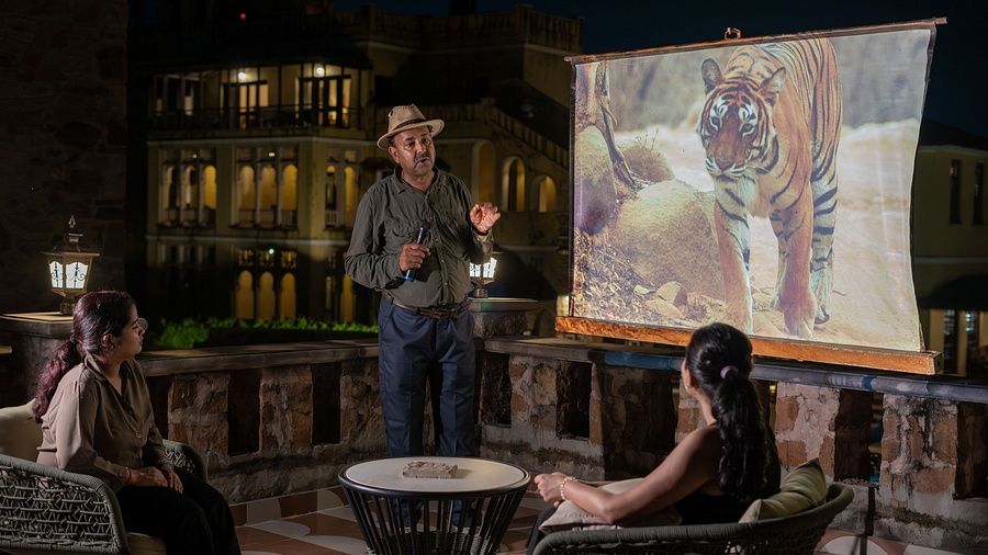 Picture of a naturalist giving a presentation to guests outdoors, with a tiger image projected on the screen.