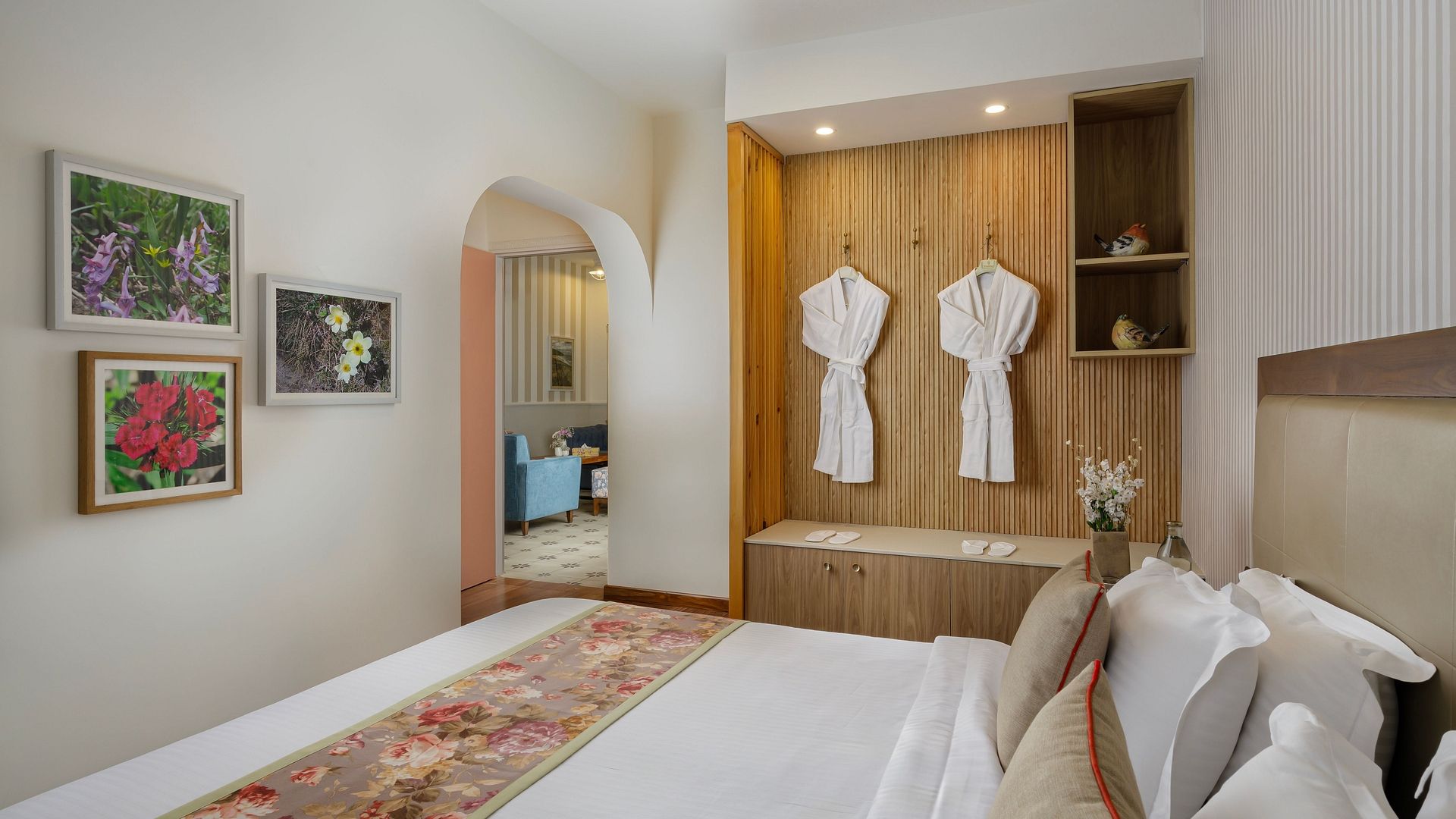 A bedroom at Karma Chalets with a bed, open wardrobe with bathrobes, and framed pictures on the wall.