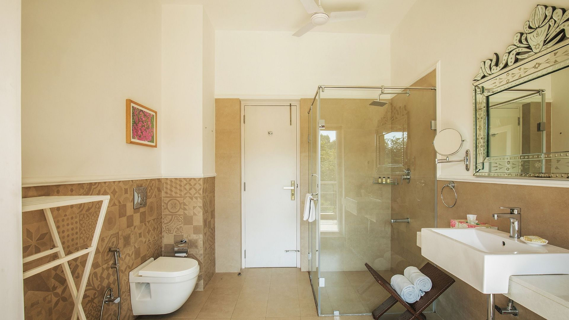 A bathroom at Karma Chalets with a toilet, sink, glass shower enclosure, and wall mirror.