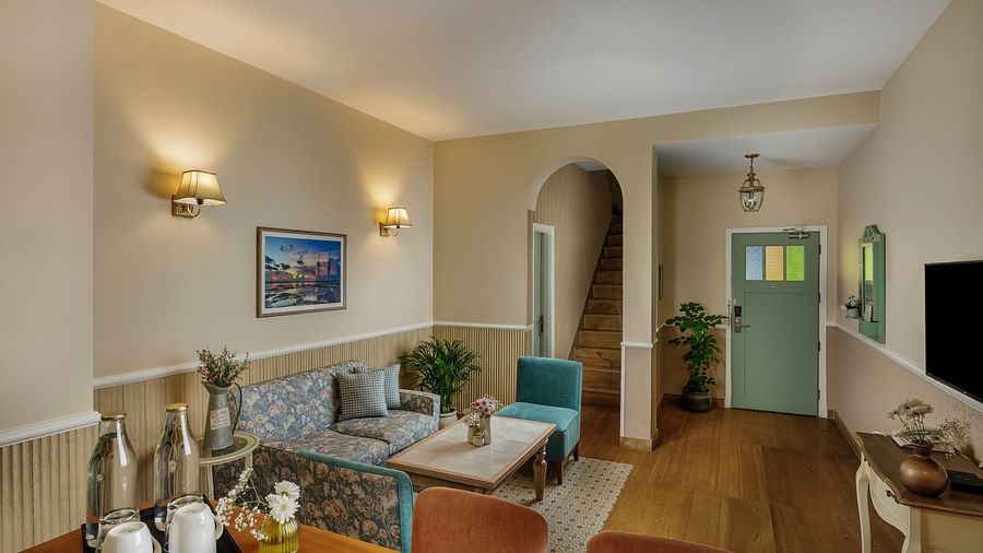 A living area at Karma Chalets with sofas, a central table, and arched doorway leading to another room.
