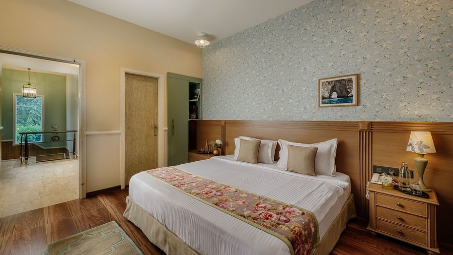 A bedroom at Karma Chalets with a large bed, two nightstands, and patterned wallpaper.