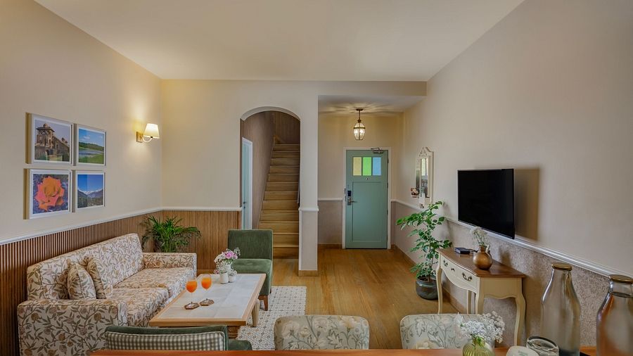A lounge area at Karma Chalets with multiple sofas, chairs, a TV, and a central wooden table.