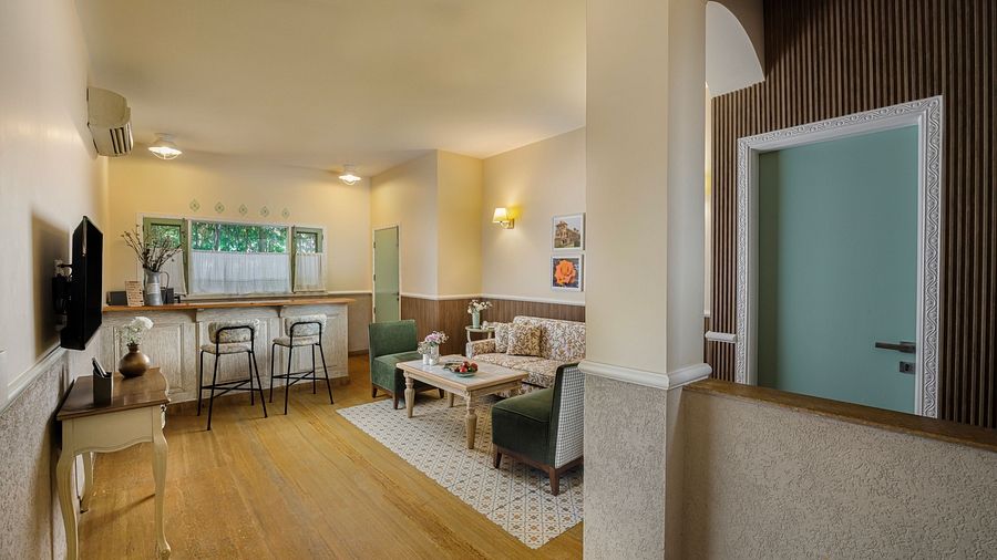 An indoor area at Karma Chalets with a dining table, seating, kitchenette, and wall-mounted TV.