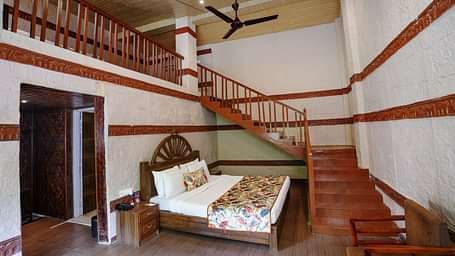 Duplex ethnic villa featuring a spacious bedroom and staircase leading to an additional room at Summit Green Lake Tea Resort & Spa, Kaziranga