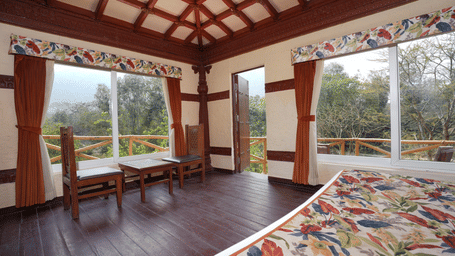 Ethnic villa featuring a spacious bed with wooden furniture at Summit Green Lake Tea Resort & Spa, Kaziranga.