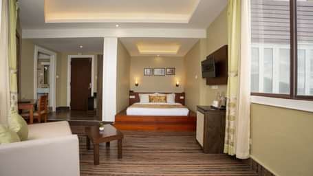 Honeymoon Suite with Valley View at Summit North Star, Gangtok featuring a bed in one coner, a cabinet table, flat TV screen on the wall, a sofa and a centre table.