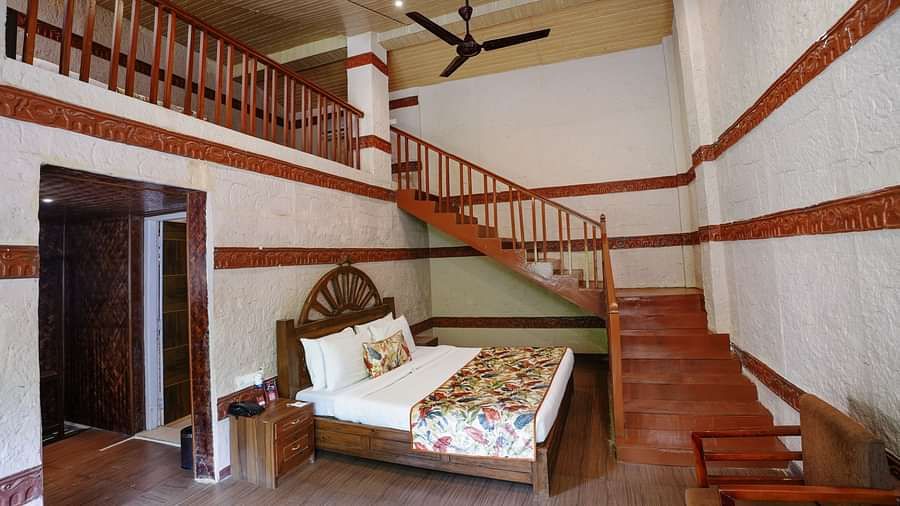 Duplex ethnic villa featuring a spacious bedroom and staircase leading to an additional room at Summit Green Lake Tea Resort & Spa, Kaziranga