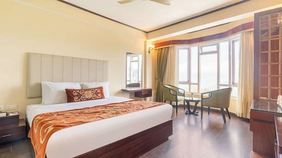 king size bed and chairs in the background near balcony of premium room at Summit Lillium Hotel & Spa, Kalimpong