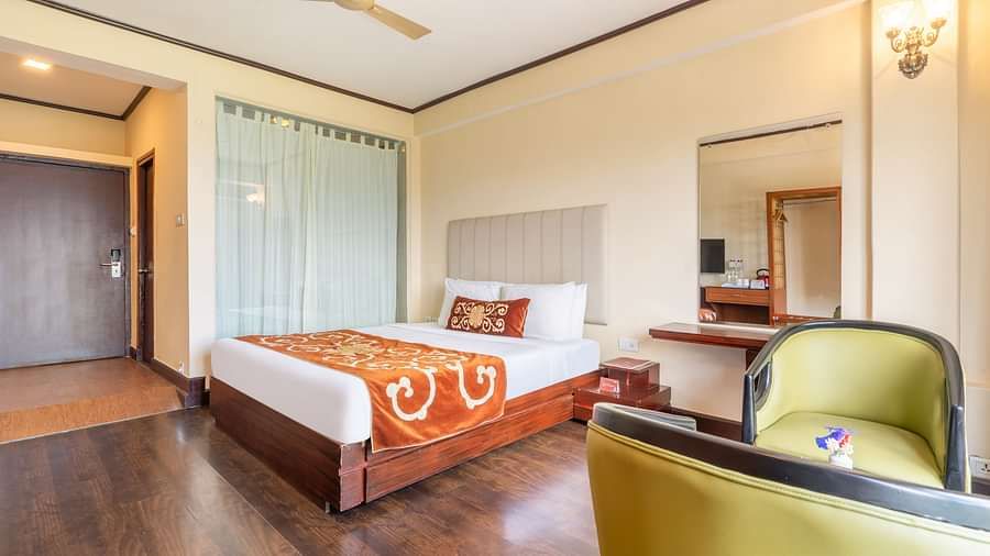 king size bed and chairs of premium room at Summit Lillium Hotel & Spa, Kalimpong