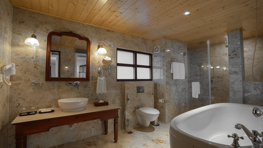 A bathroom at Summit Norbu Ghang - The Signature Collection, Gangtok, with bathtub, sink counter, mirror, and tiled flooring.