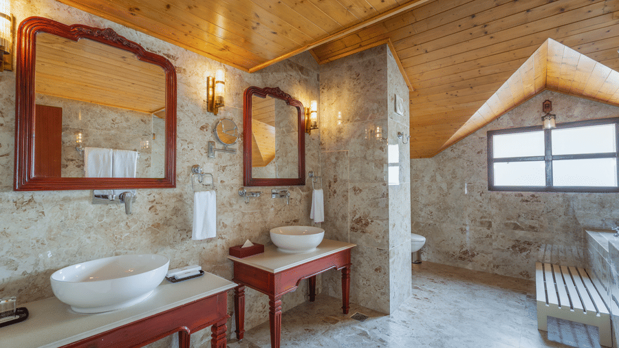 A bathroom at Summit Norbu Ghang - The Signature Collection, Gangtok, with wash basin, mirror, window, and stone-finished walls.