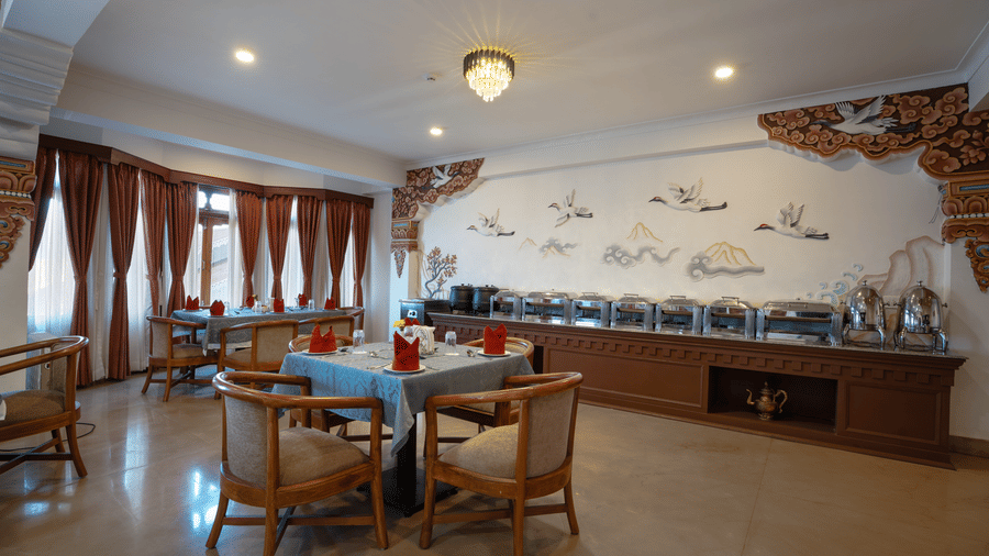 The restaurant interior at Summit Norbu Ghang - The Signature Collection, Gangtok, with buffet counter, dining tables, chairs, and wall art.