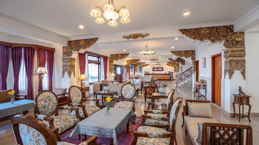 A restaurant dining area at Summit Norbu Ghang - The Signature Collection, Gangtok, with arranged tables, upholstered chairs, chandeliers, and buffet counter.