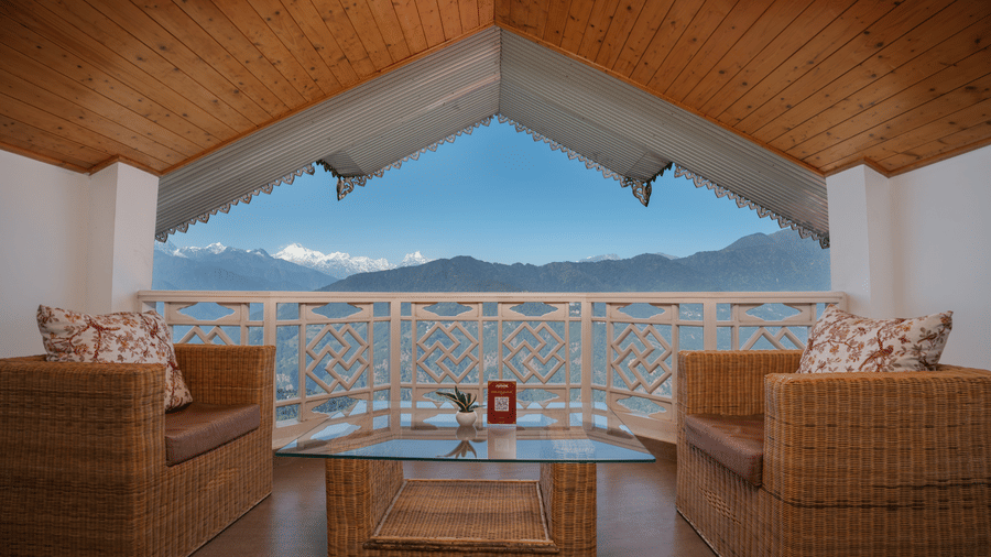 A balcony seating area at Summit Norbu Ghang - The Signature Collection, Gangtok, with 2 armchairs, table, and mountain view.