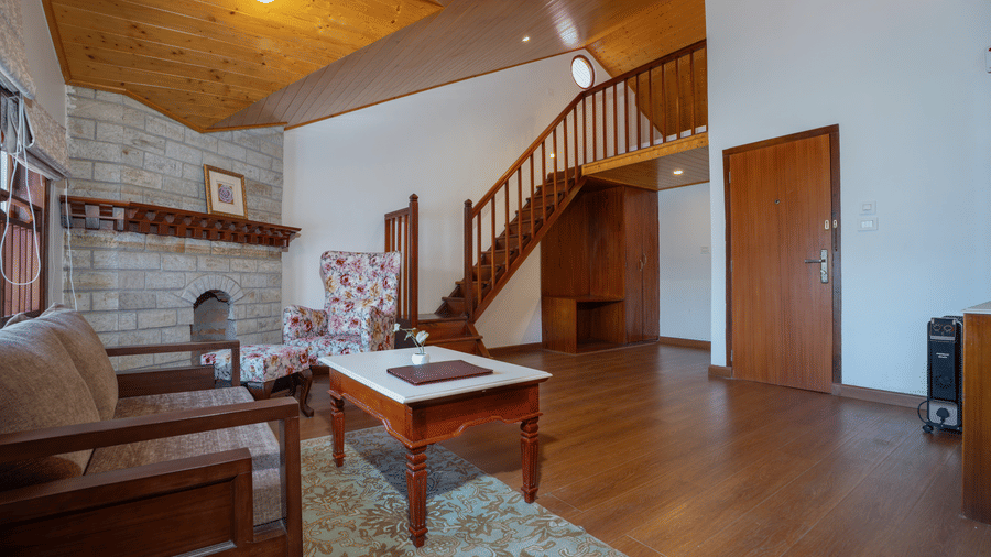 The living area at Summit Norbu Ghang - The Signature Collection, Gangtok, with a sofa, coffee table, staircase, and chair.