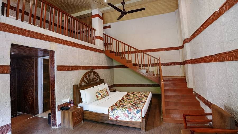 Duplex ethnic villa featuring a spacious bedroom and staircase leading to an additional room at Summit Green Lake Tea Resort & Spa, Kaziranga