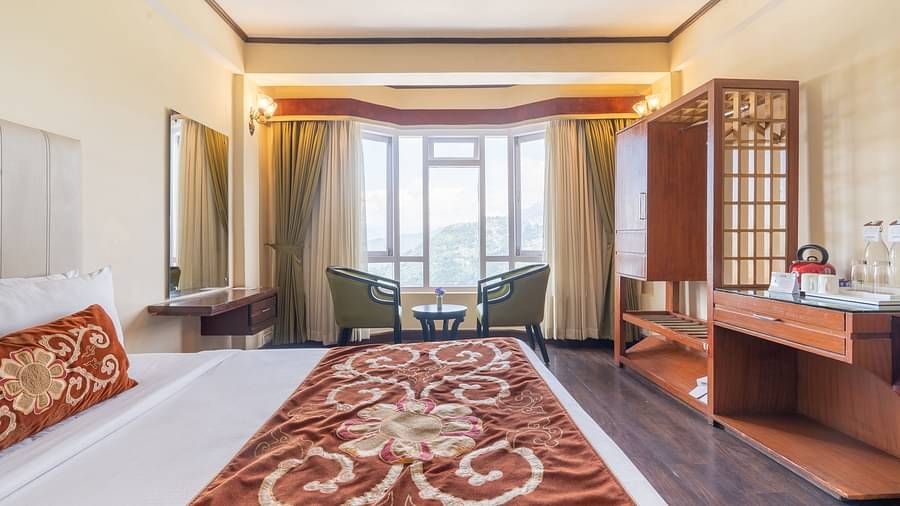 king size bed and chairs in the background near balcony of premium room at Summit Lillium Hotel & Spa, Kalimpong