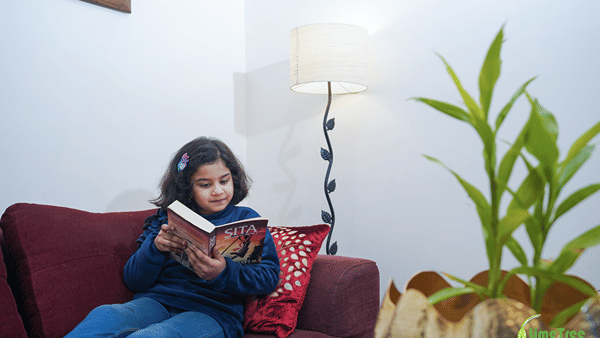 Child reading the book SITA on a maroon sofa in the seating corner of Lime Tree Hotel Near 32nd Avenue.