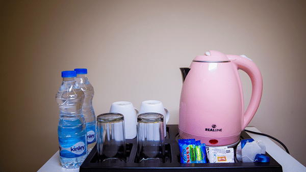Tea and coffee making tray featuring an electric kettle, glasses, and a water bottle.