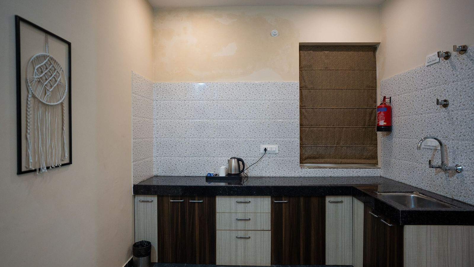 Image of a kitchen with a kettle placed on the counter table and a frame on the walll at Aanandam Resort & Spa, Pushkar.
