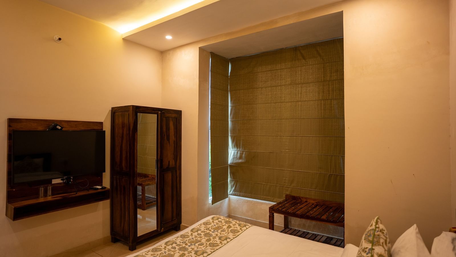 Image of a room with a bed, television, and wardrobe in front of it at Aanandam Resort & Spa, Pushkar.
