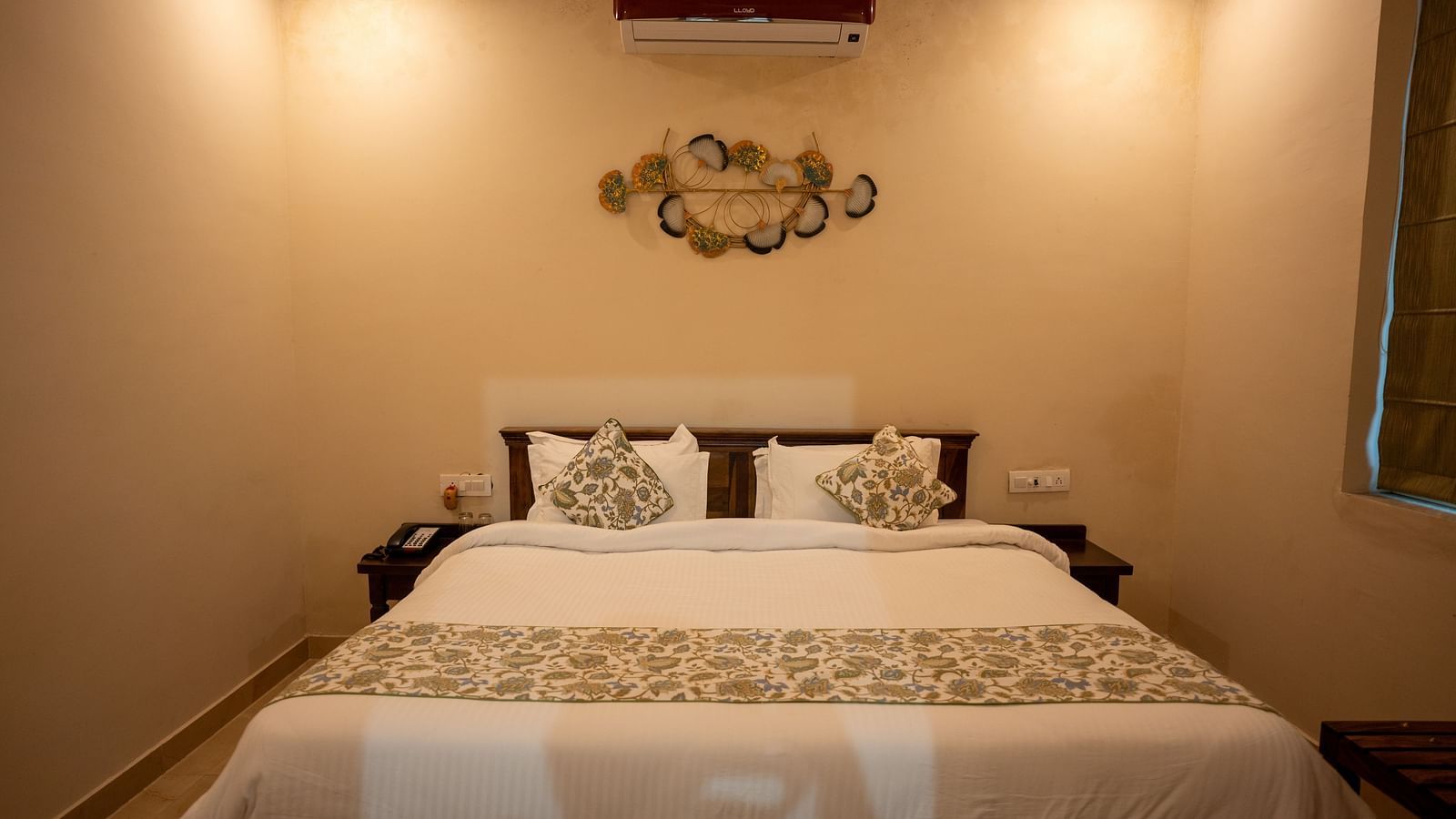 Image of a bed with pillows on it and air-conditioner above it at Aanandam Resort & Spa, Pushkar.