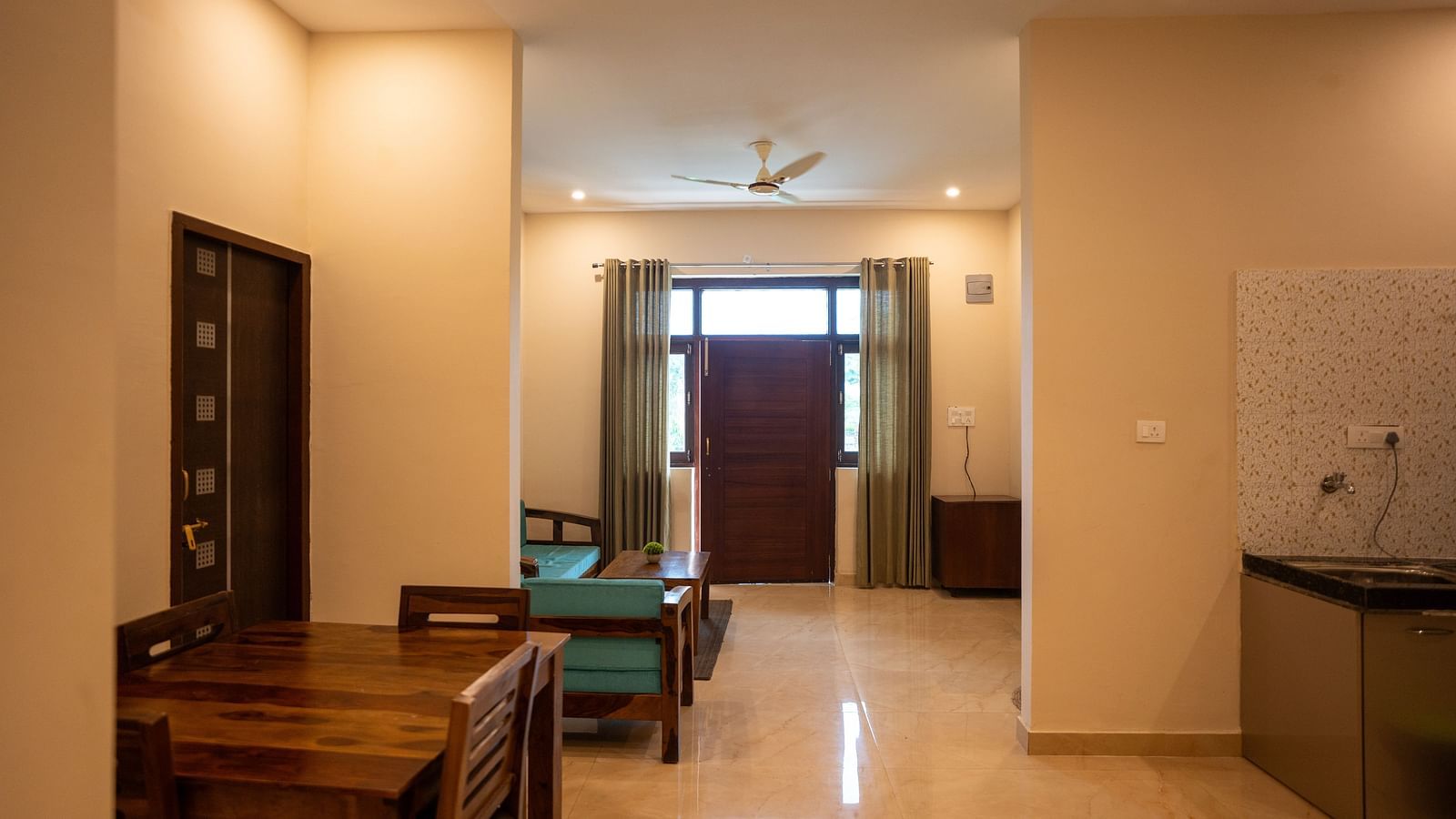 Image of a room with dining table and seating area behind it at Aanandam Resort & Spa, Pushkar.