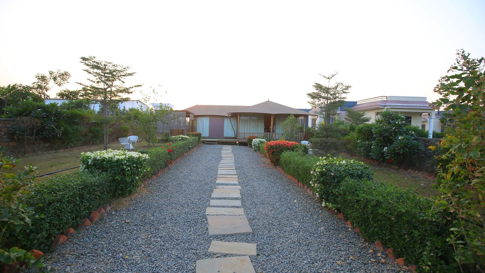 Front view of the Luxury Wooden Tent, with vibrant plants lining the pathway at Aanandam Resort & Spa
