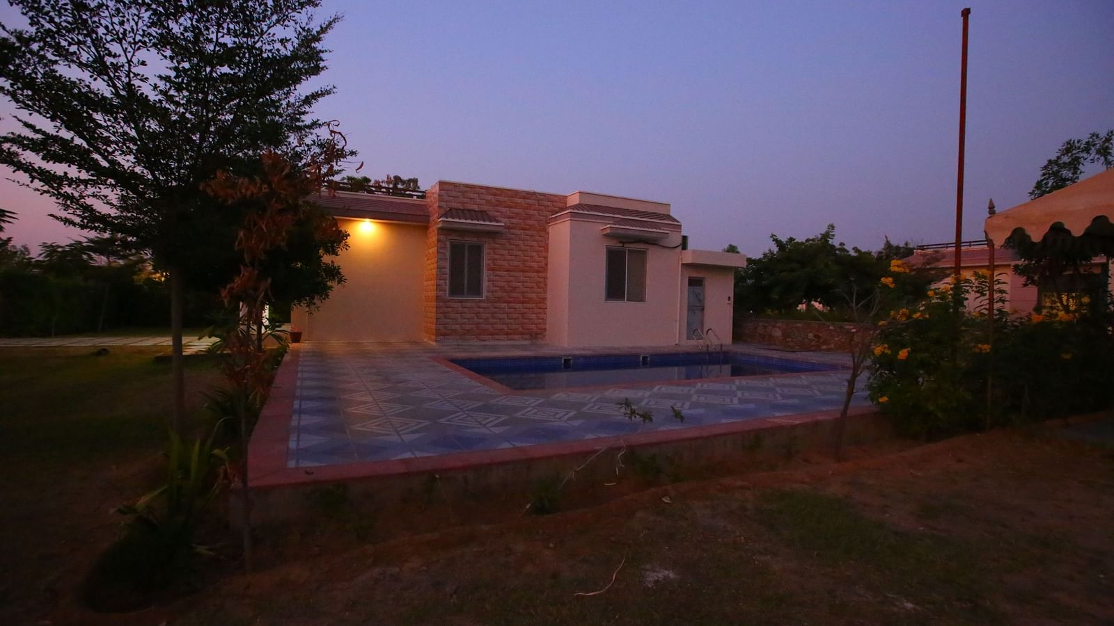 Facade of the Family Party Villa with Pool at Aanandam Resort & Spa, illuminated under a sunset sky with warm lights enhancing the building's charm