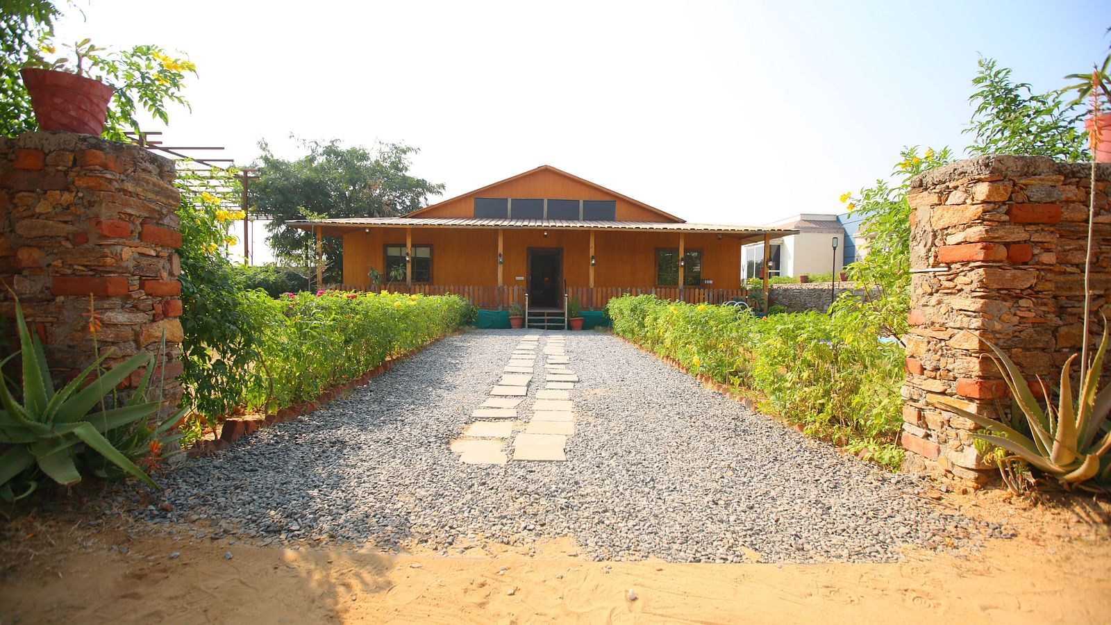 Facade of Kashmir Cottage Villa's Pool room with a pathway adorned with plants at Aanandam Resort & Spa