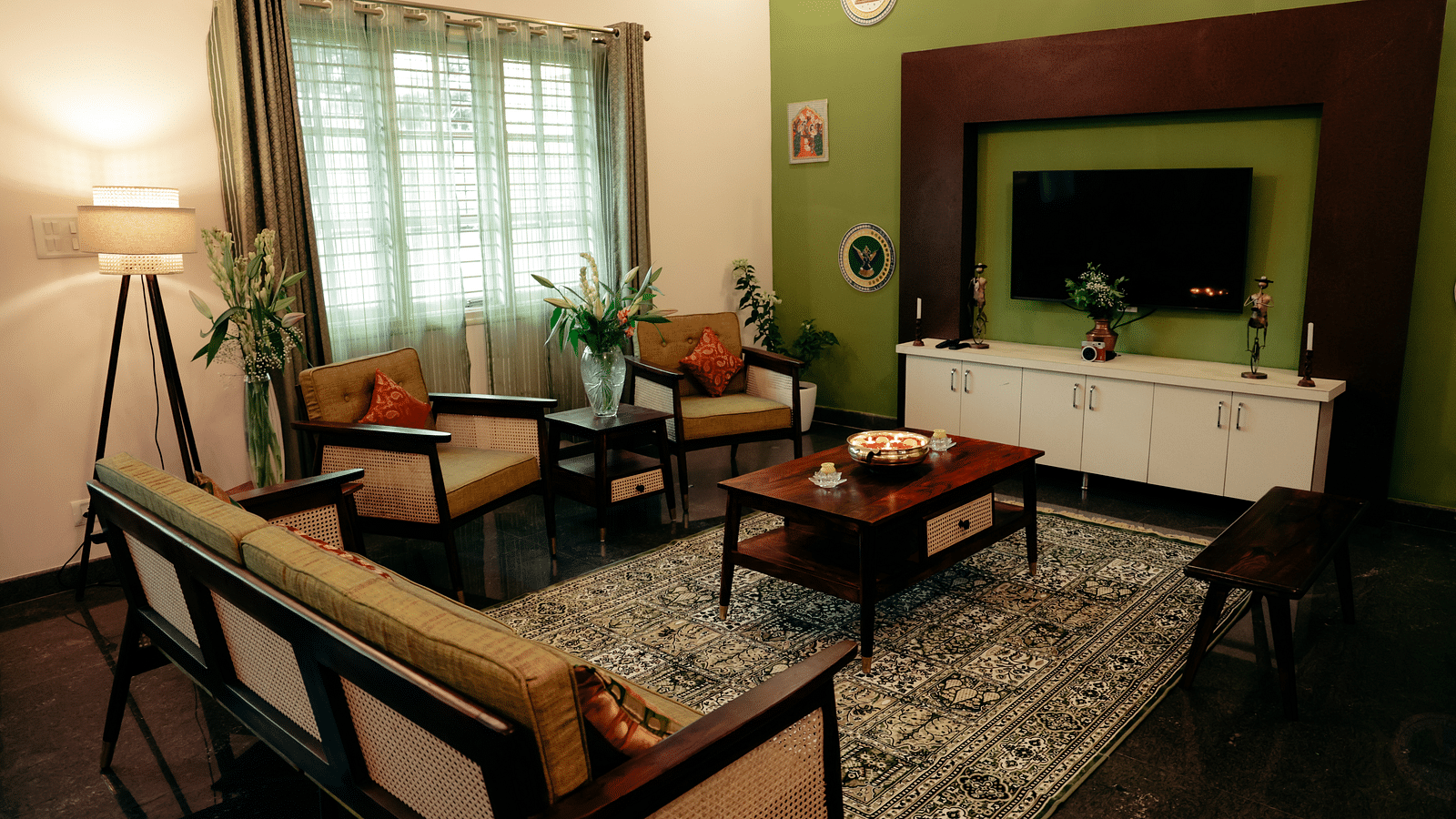A living room with a green accent wall, a TV mounted on it, and a brown sofa set | Adhyaya Heritage Reverbed