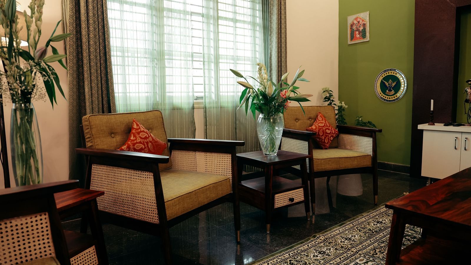 Two armchairs facing each other in a living room, with a small table between them and a larger table in the foreground | Adhyaya Heritage Reverbed