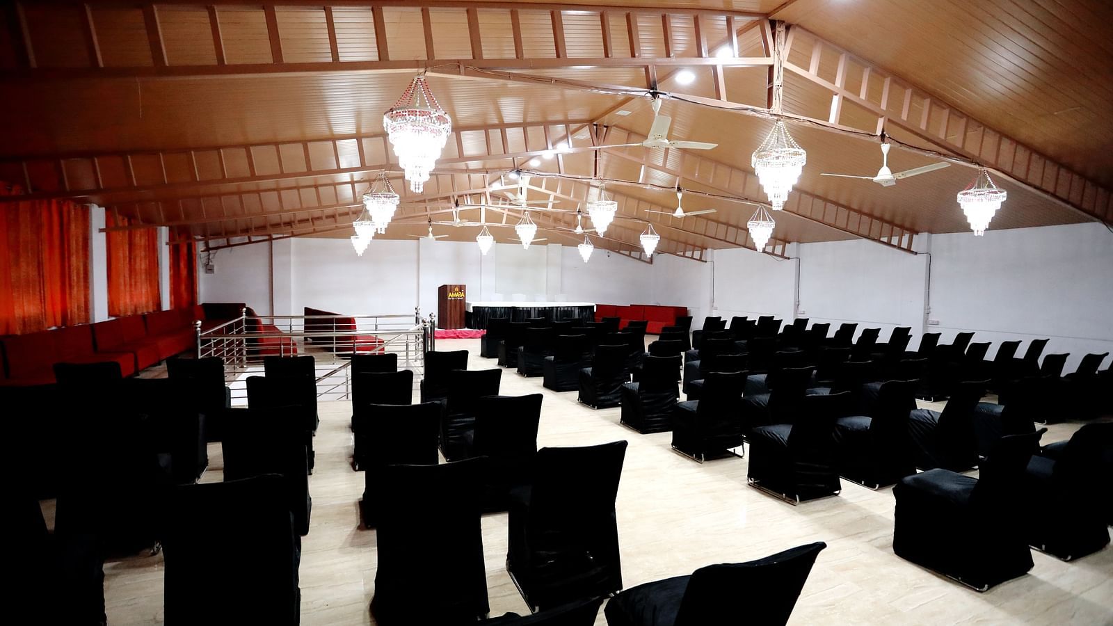 Image of a banquet hall with chairs neatly lined and lights hanging from the ceiling at Amara Hill Queen, Mussoorie.