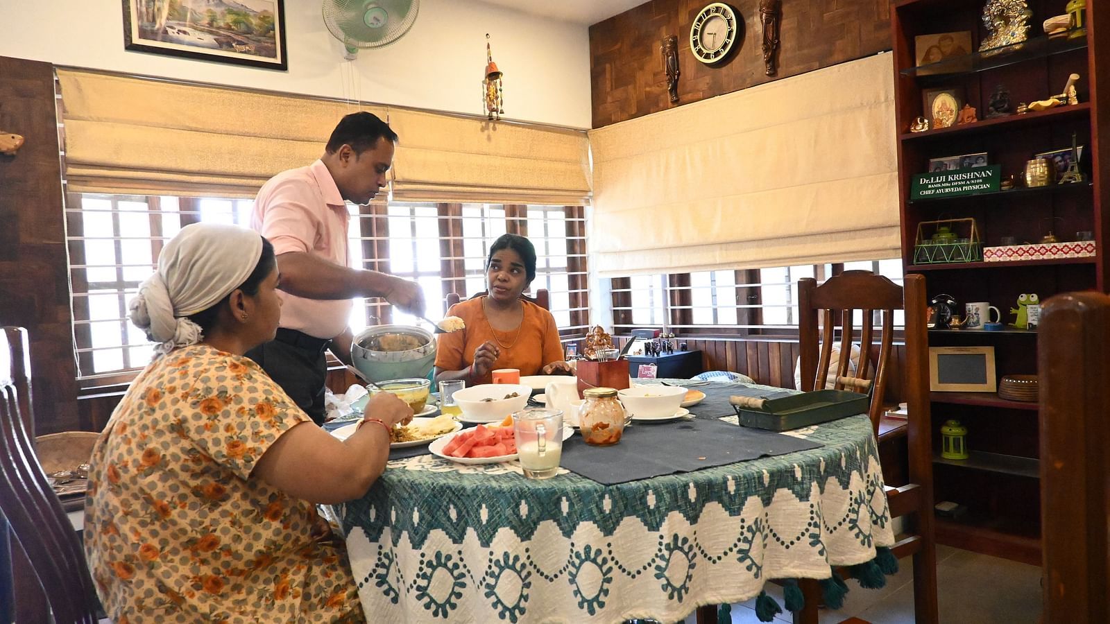 A man serving food to two women at Ananda Holiday Home, Wayanad