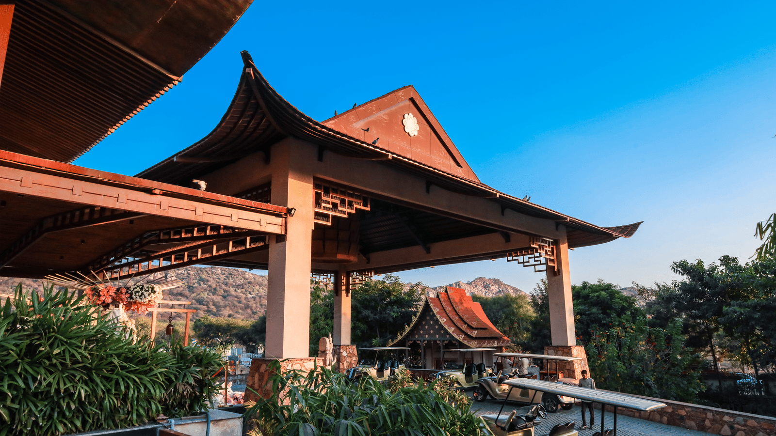 The exterior entrance of Ananta Spa & Resort, Jaipur, showcases its distinctive pagoda-style architecture against a bright blue sky.