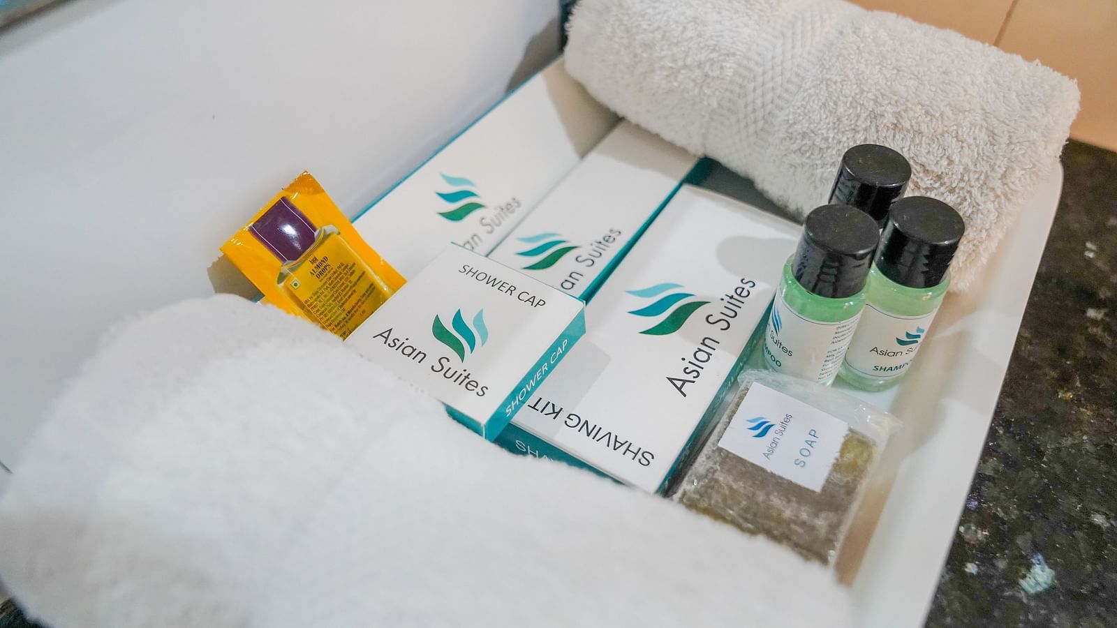 A close-up of a neatly arranged set of toiletries on a white towel, including small bottles and soaps - Asian Suites Cyber Park, Gurgaon