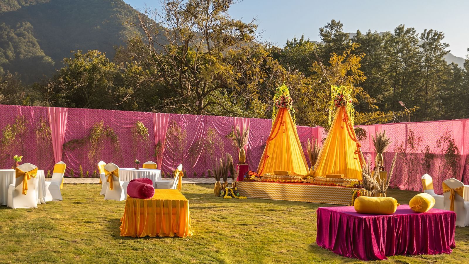 Vibrant Indian wedding decor with colorful tent, patterned floor, and seating, showcasing traditional festive setup.