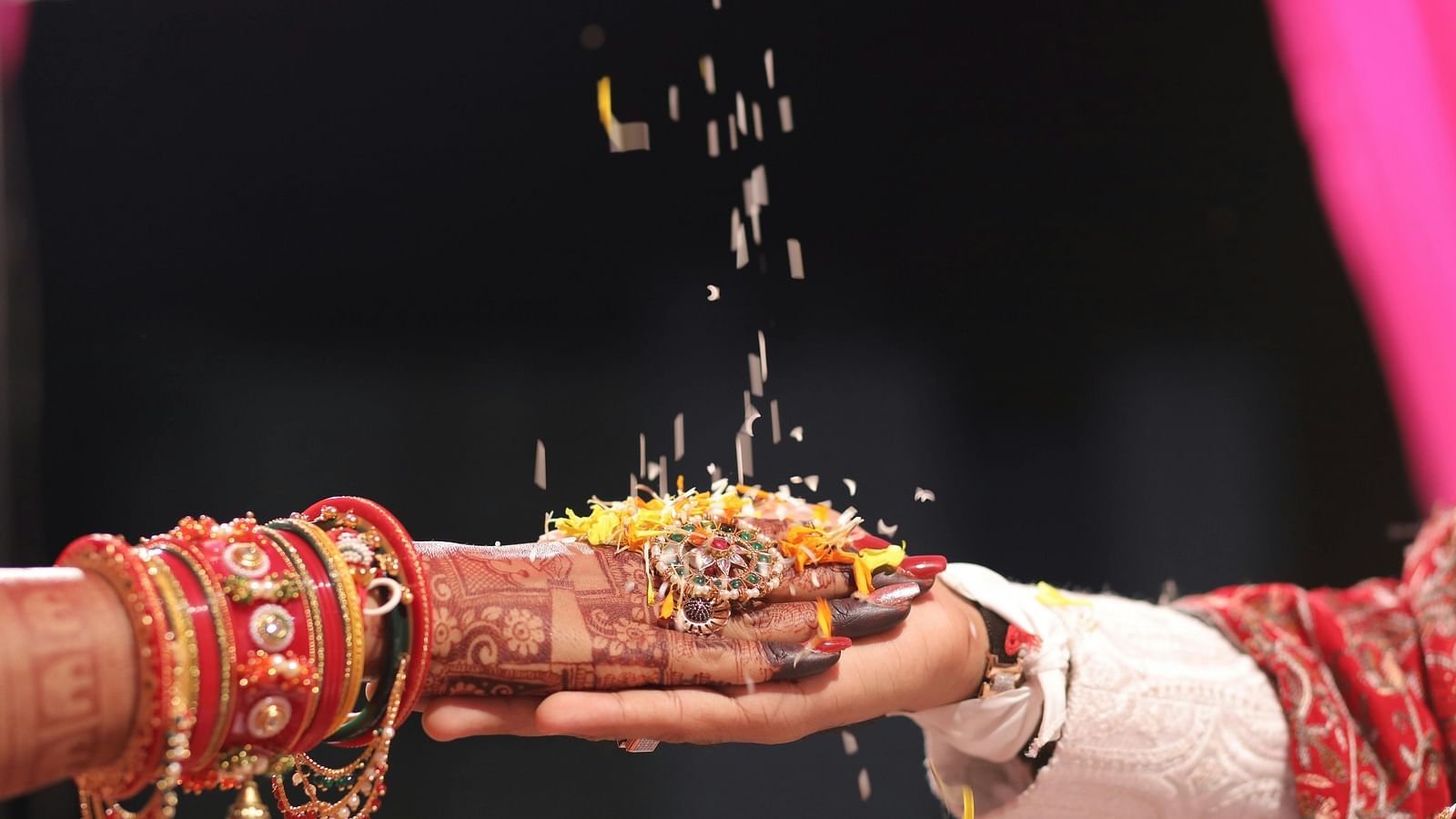 Close-up of hands during an Indian wedding ritual, with rice grains being poured, symbolizing tradition and blessing.