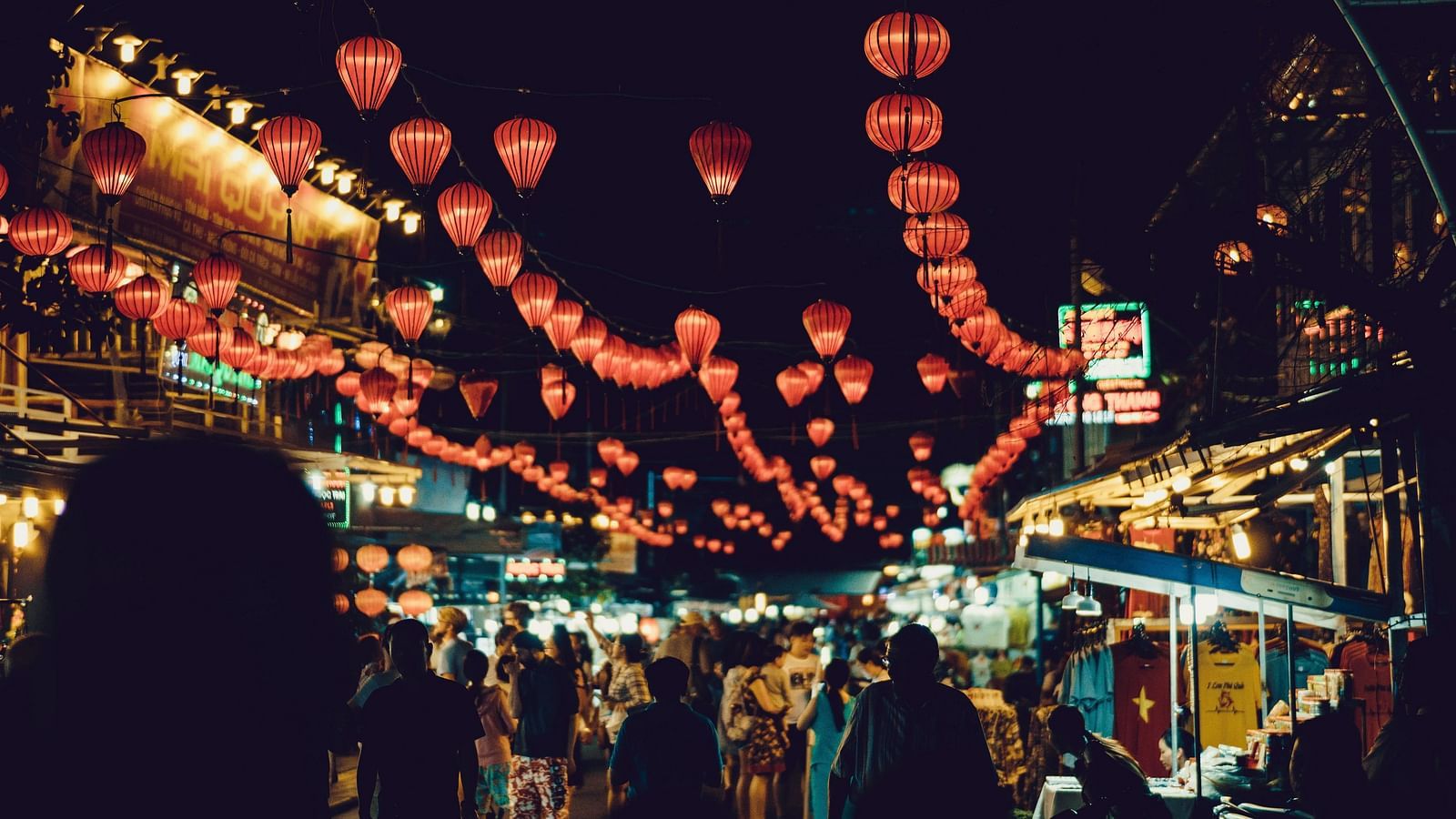 A night market filled with people and lighted lanterns.