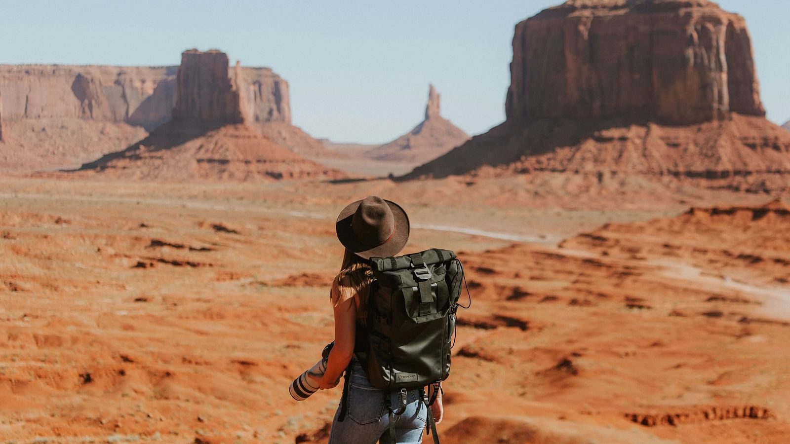 A woman with backpack on a trek in the desert.