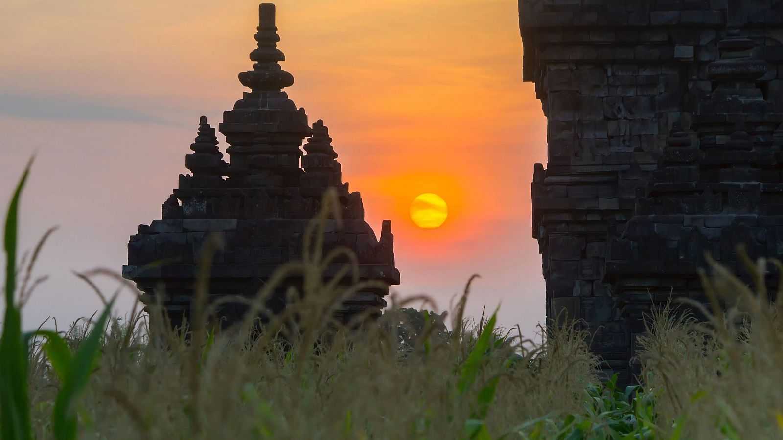Ancient structure at sunset, with grass in the foreground.