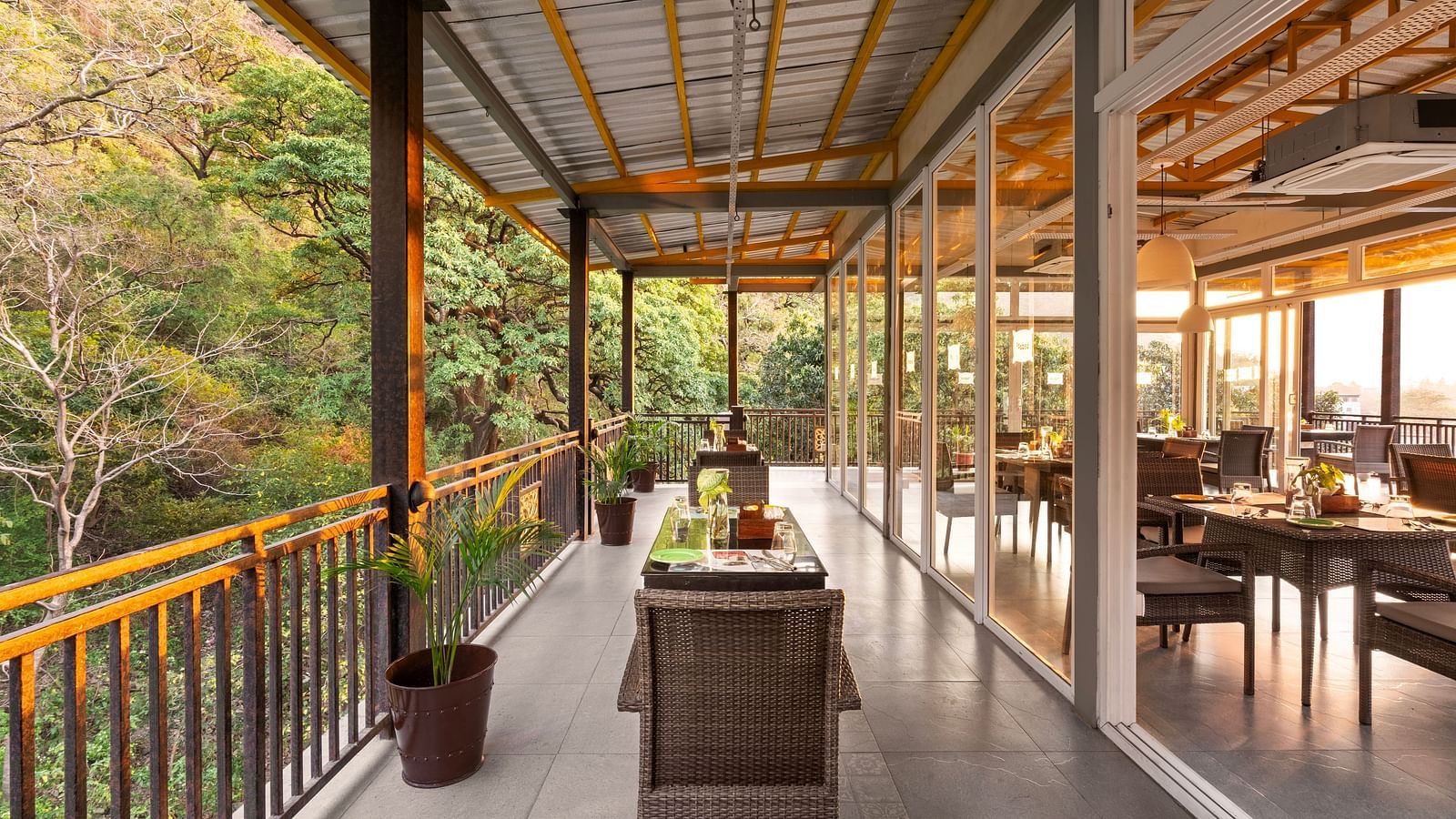 Balcony dining scene overlooking lush forest, with table set and chairs at Bedzzz, Rishikesh