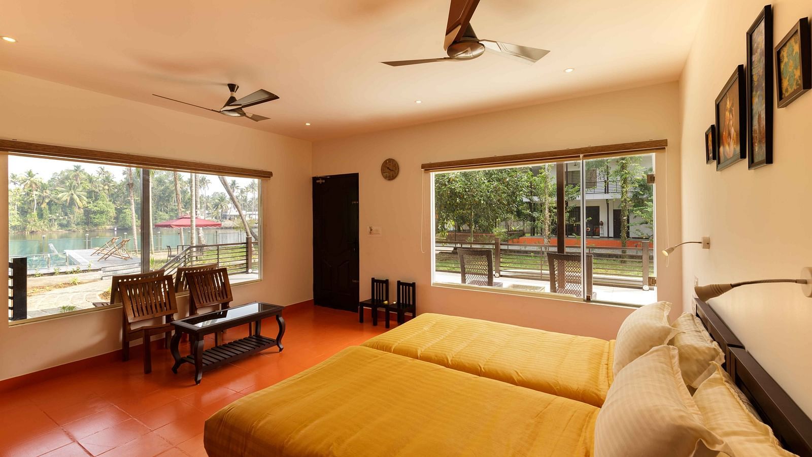 A bedroom with two beds, a seating area by a window, and ceiling fans.