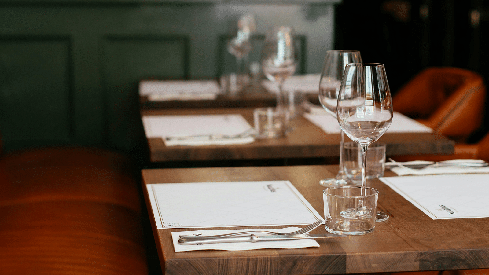 A dining setup with clear glasses placed near the menus on a wooden table.